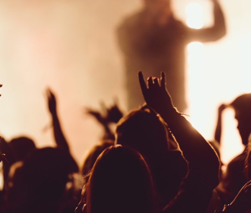 People dancing at a concert while the singer is performing surrounded with lights