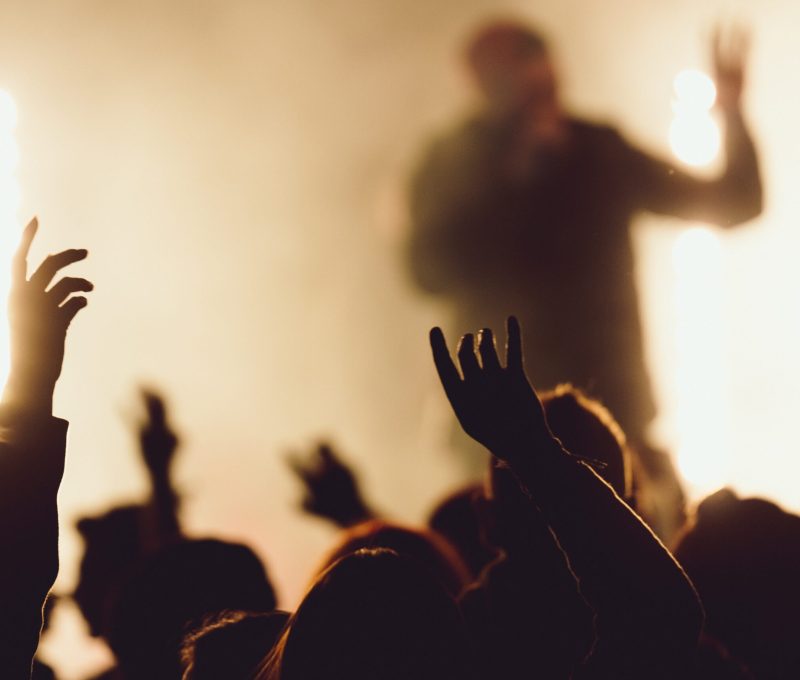 People dancing at a concert while the singer is performing surrounded with lights